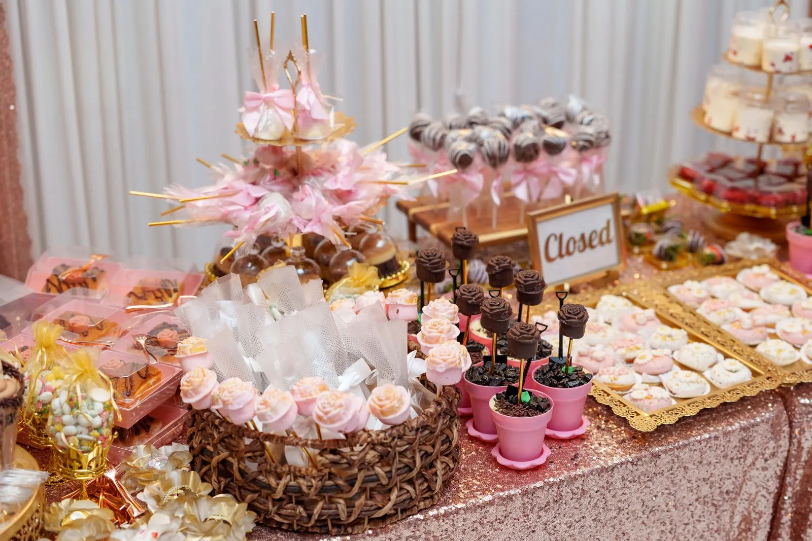 Una mesa de dulces y postres de quinceañera en oro rosa montada en el salón de Luxor Banquet Hall