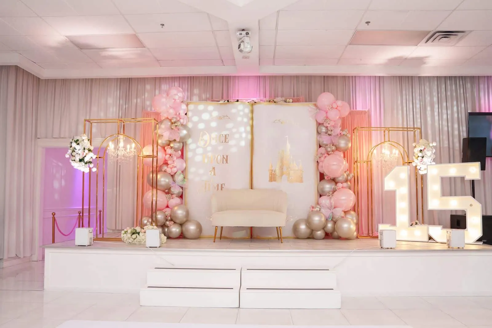 A stage with a fairytale backdrop, balloons and lighting at Luxor Banquet Hall
