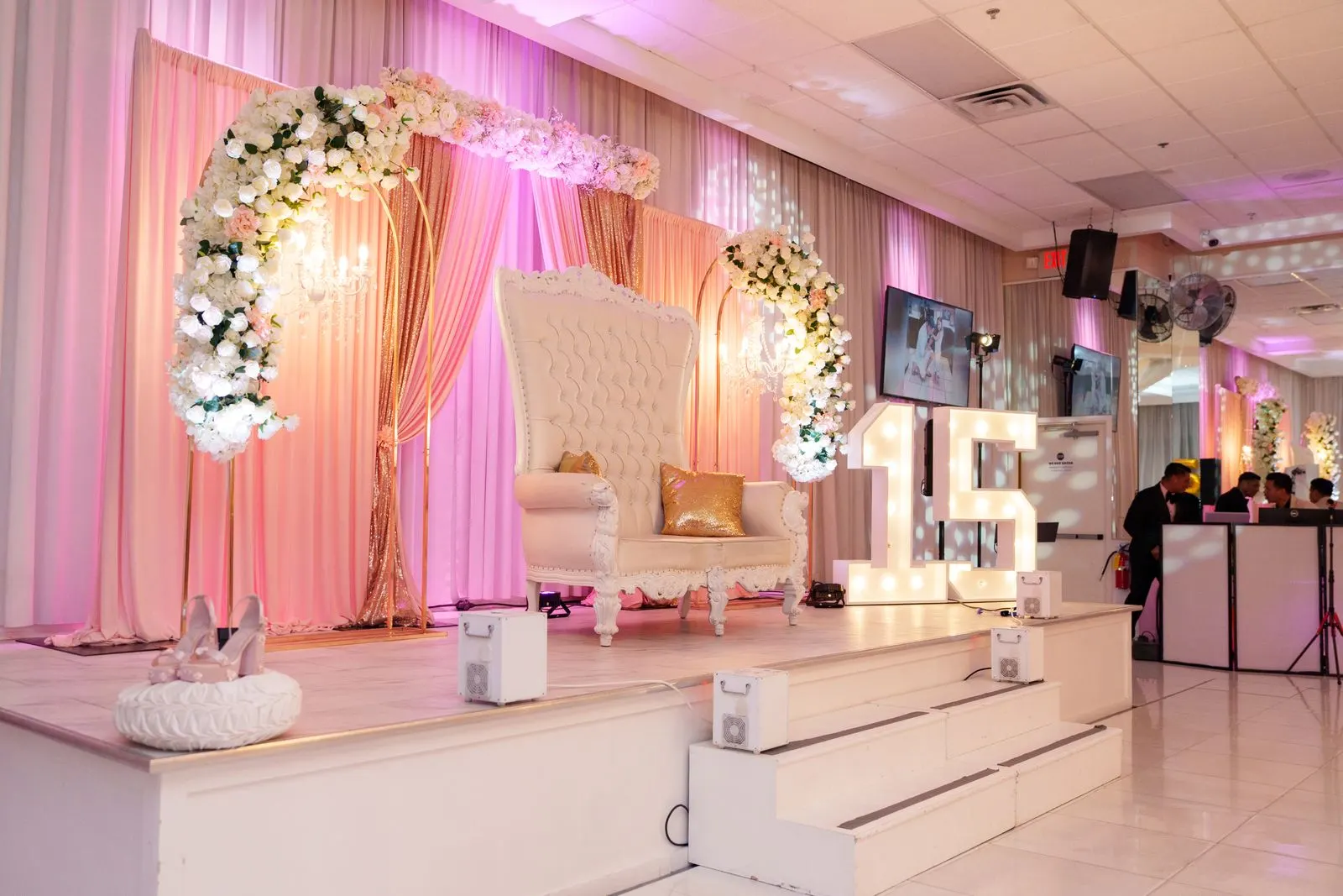 The quinceañera throne and stage setup with floral arches at Luxor Banquet Hall